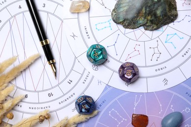 Photo of Zodiac wheels, natal chart, fountain pen, astrology dices and gemstones, flat lay