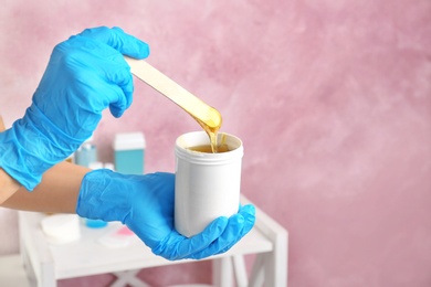Photo of Woman with wooden stick and sugaring paste indoors, closeup