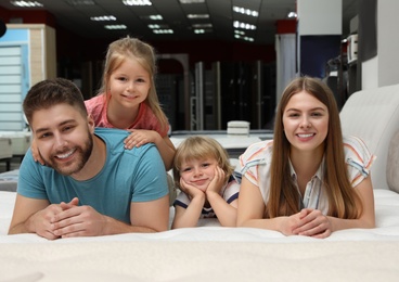 Photo of Happy family lying on new orthopedic mattress in store