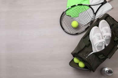 Photo of Sports bag and tennis equipment on wooden background, flat lay. Space for text