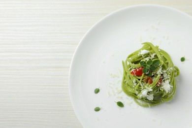 Photo of Tasty tagliatelle with spinach and cheese served on white wooden table, top view and space for text. Exquisite presentation of pasta dish