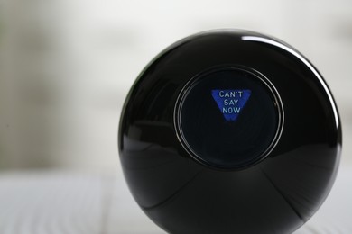 Photo of Magic eight ball with prediction Can't Say Now on light background, closeup. Space for text