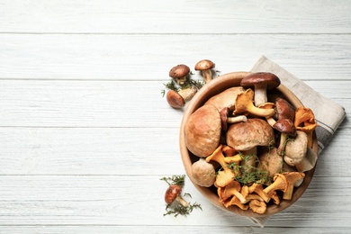 Photo of Different fresh wild mushrooms on white wooden table, flat lay. Space for text