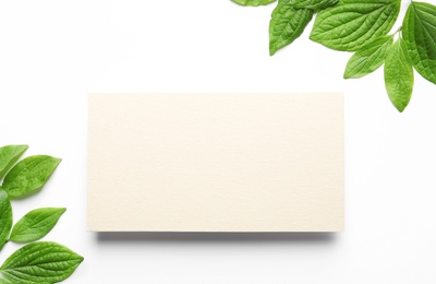 Photo of Blank card and spring green leaves on white background, top view. Space for text