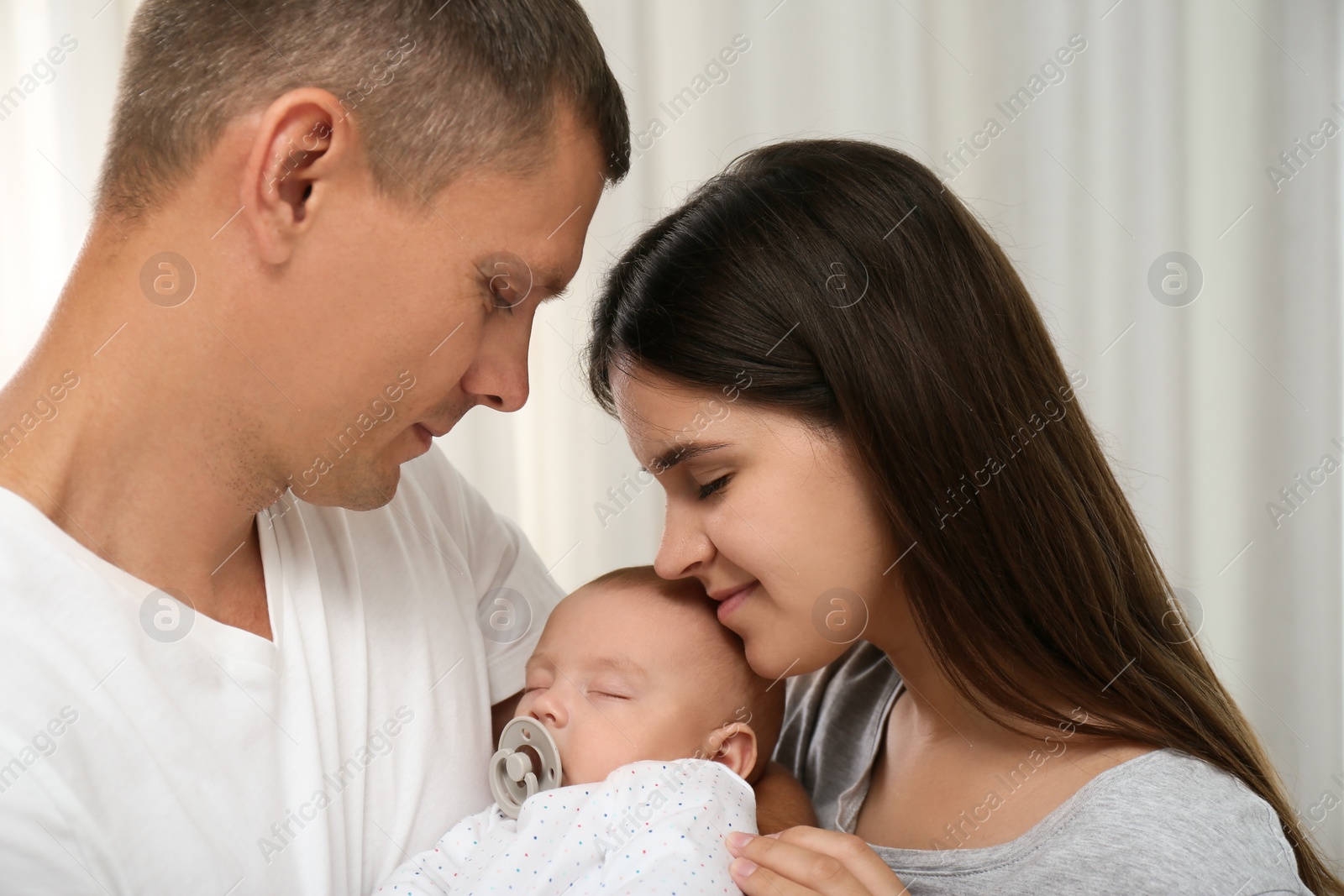 Photo of Happy family with their cute sleeping baby indoors