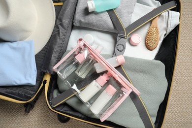 Photo of Plastic bag of cosmetic travel kit in suitcase, top view