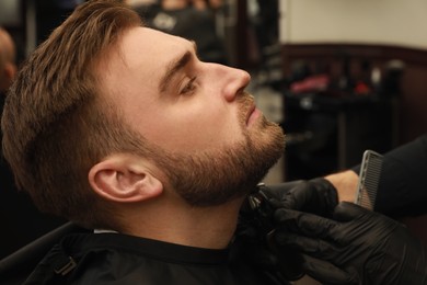Photo of Professional hairdresser working with client in barbershop