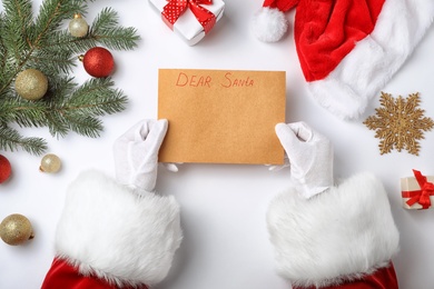 Photo of Santa Claus reading letter from child at table, top view. Christmas celebration