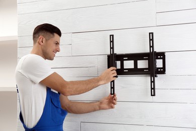 Photo of Professional technician installing TV bracket on wall indoors
