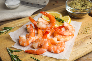 Photo of Delicious cooked shrimps with rosemary on wooden board