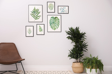 Photo of Beautiful paintings of tropical leaves on white wall in living room interior