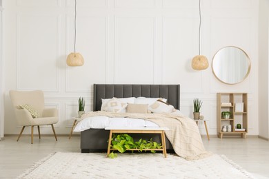 Photo of Stylish bedroom interior with large comfortable bed, armchair and mirror