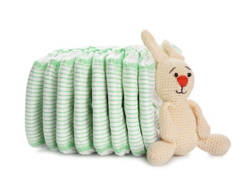 Photo of Disposable diapers and toy bunny on white background. Baby accessories