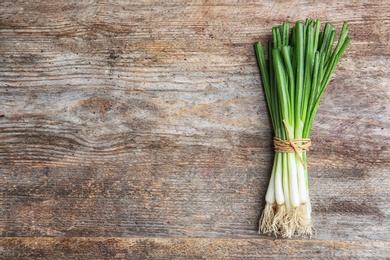 Photo of Tied fresh green onion on wooden table, top view