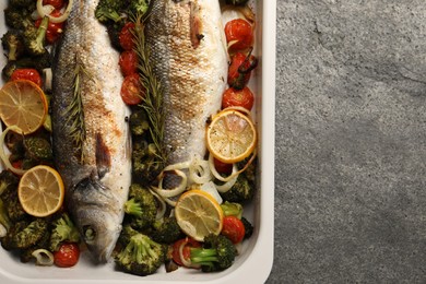Photo of Delicious fish with vegetables and lemon in baking dish on grey textured table, top view. Space for text