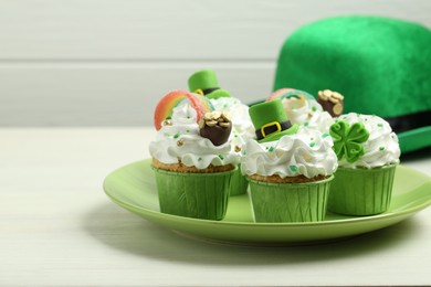 Photo of St. Patrick's day party. Tasty festively decorated cupcakes on white table, closeup. Space for text