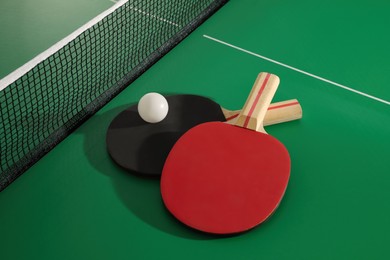 Photo of Rackets and ball near net on ping pong table