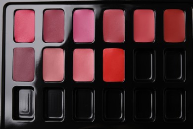Photo of Cream lipstick palette as background, top view. Professional cosmetic product