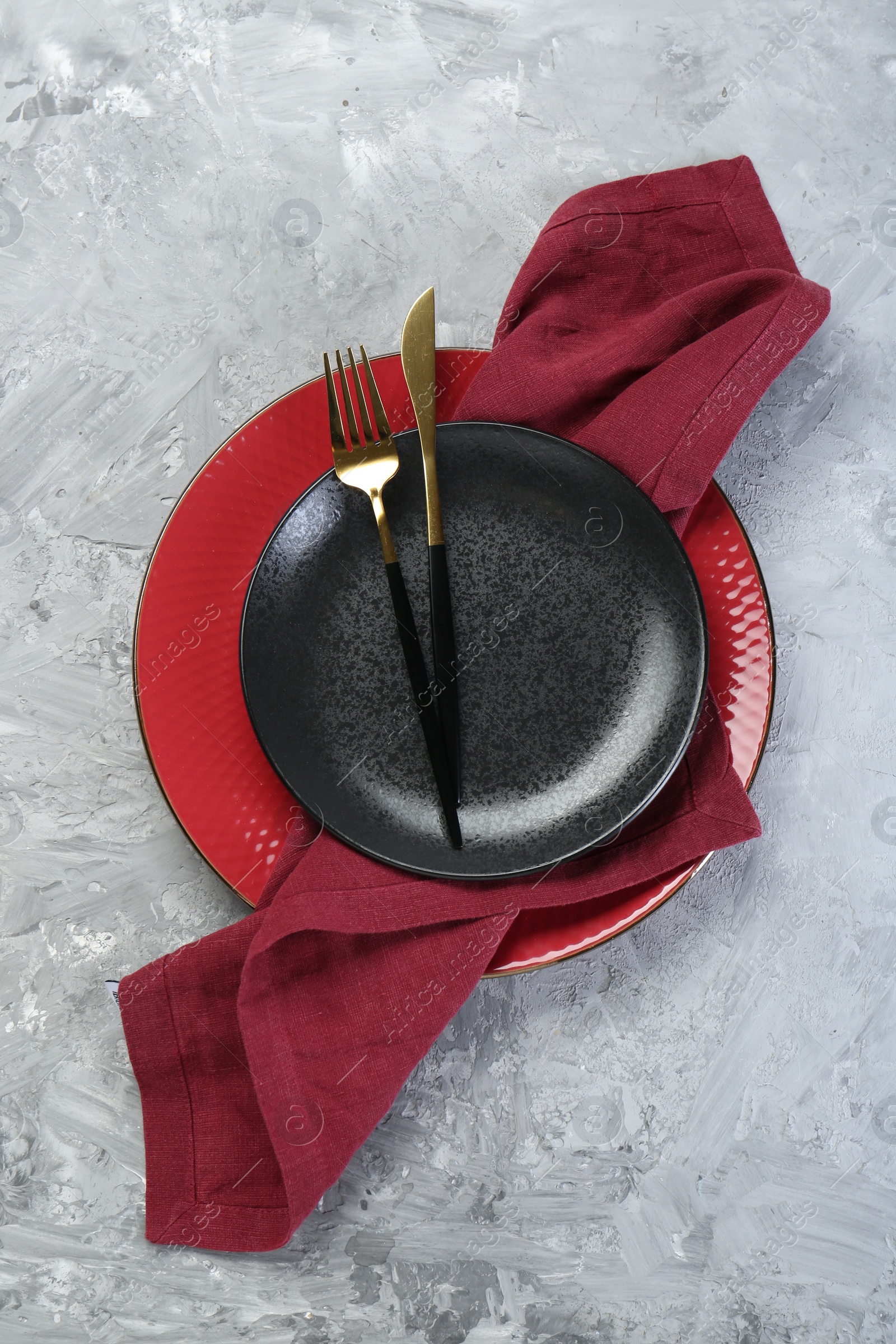 Photo of Clean plates, cutlery and napkin on gray textured table, top view