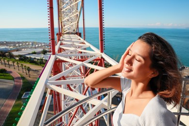 Photo of Portrait of happy young woman on Ferris wheel near sea