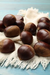 Photo of Roasted edible sweet chestnuts on light blue table, closeup