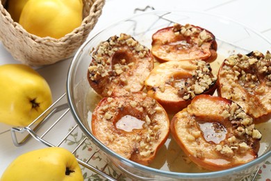 Photo of Delicious baked quinces with nuts in bowl and fresh fruits on table, closeup