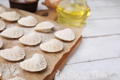 Photo of Raw dumplings (varenyky) with tasty filling on white wooden table, closeup. Space for text