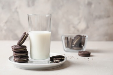 Photo of Plate with chocolate sandwich cookies and milk on table against grey background. Space for text