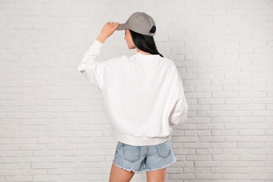 Photo of Young woman in sweater at brick wall. Mock up for design