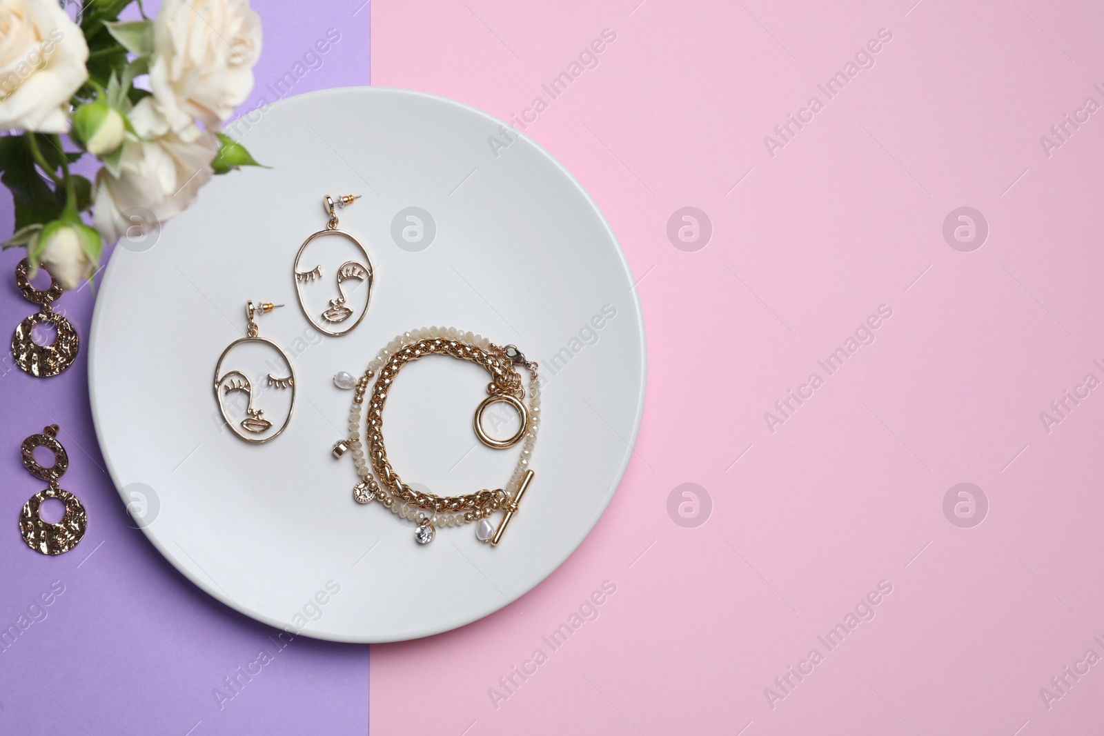 Photo of Beautiful jewelry and flowers on color background, flat lay. Space for text