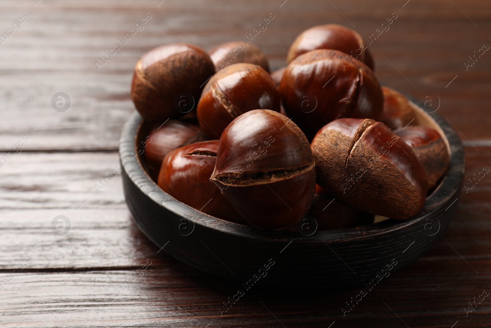 Roasted edible sweet chestnuts on wooden table, closeup Photo of Roasted edible sweet chestnuts on wooden table, closeup