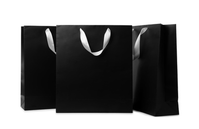 Photo of Paper shopping bags with ribbon handles on white background. Mockup for design