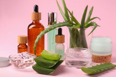Photo of Cosmetic products and cut aloe on pink background