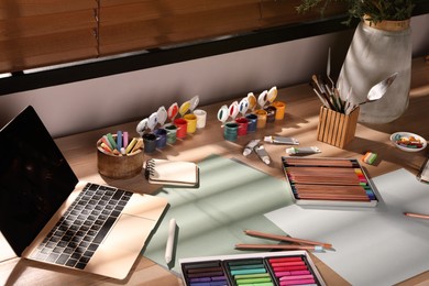 Photo of Artist's workplace with soft pastels, laptop and drawing pencils on table