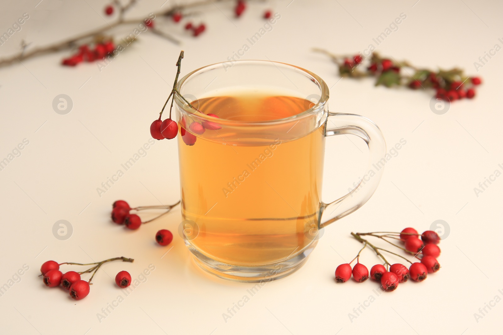 Photo of Cup with hawthorn tea and berries on beige table