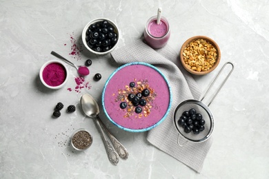 Photo of Delicious acai smoothie with granola and chia seeds served on grey table, flat lay