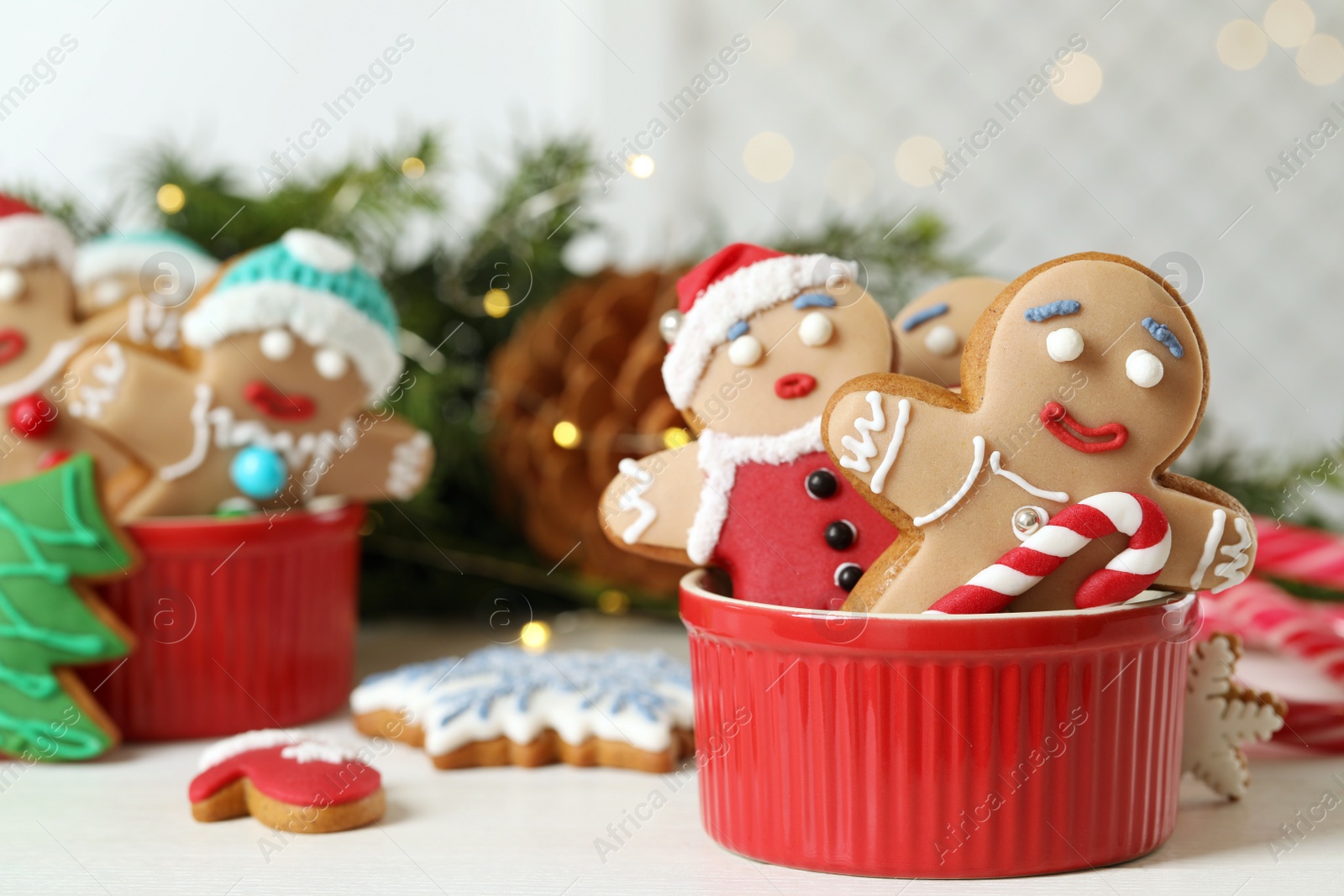 Photo of Delicious homemade Christmas cookies in bowl on white wooden table against blurred festive lights. Space for text