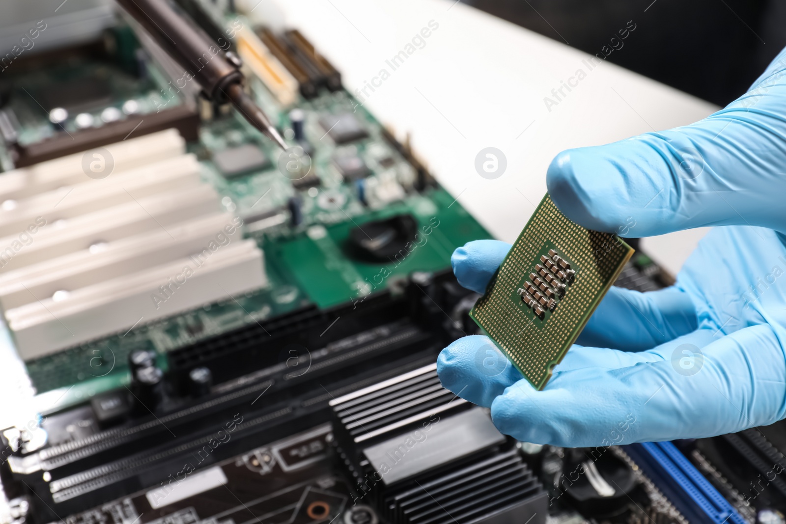 Photo of Technician repairing computer motherboard at table, closeup. Electronic device