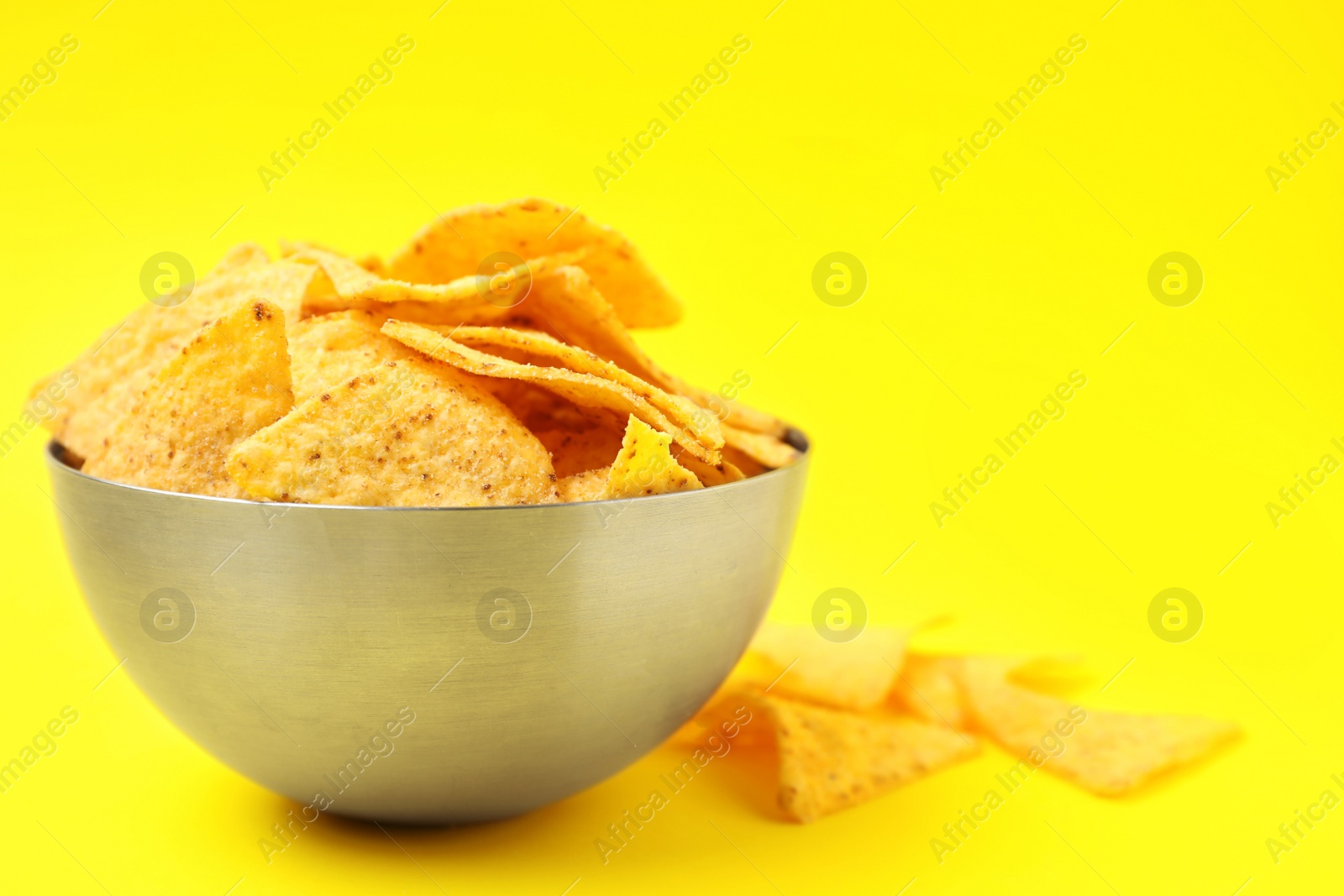 Photo of Bowl of tasty Mexican nachos chips on yellow background