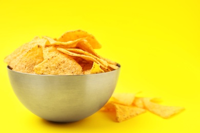 Photo of Bowl of tasty Mexican nachos chips on yellow background