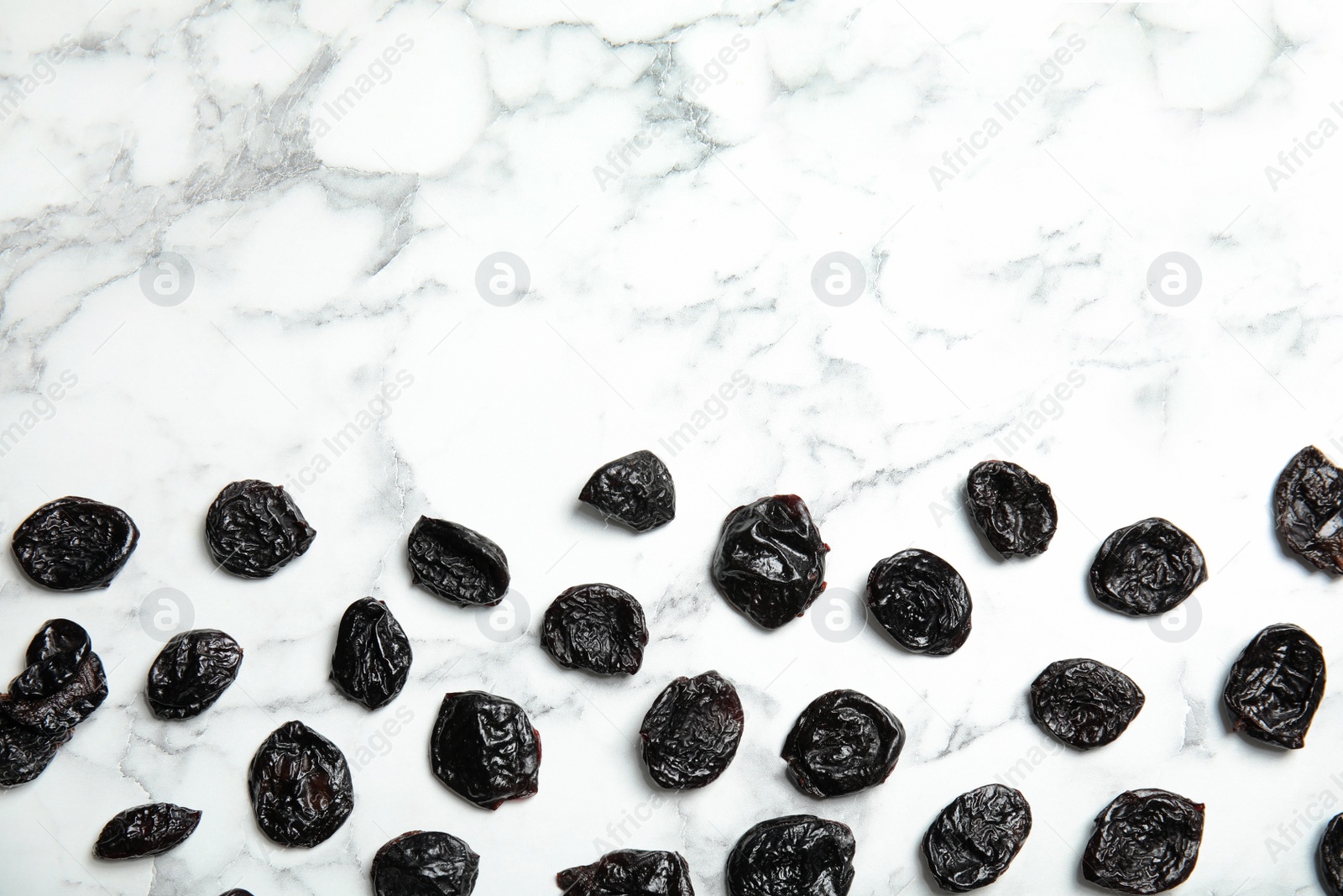 Photo of Flat lay of dried plums with space for text on marble background. Healthy fruit