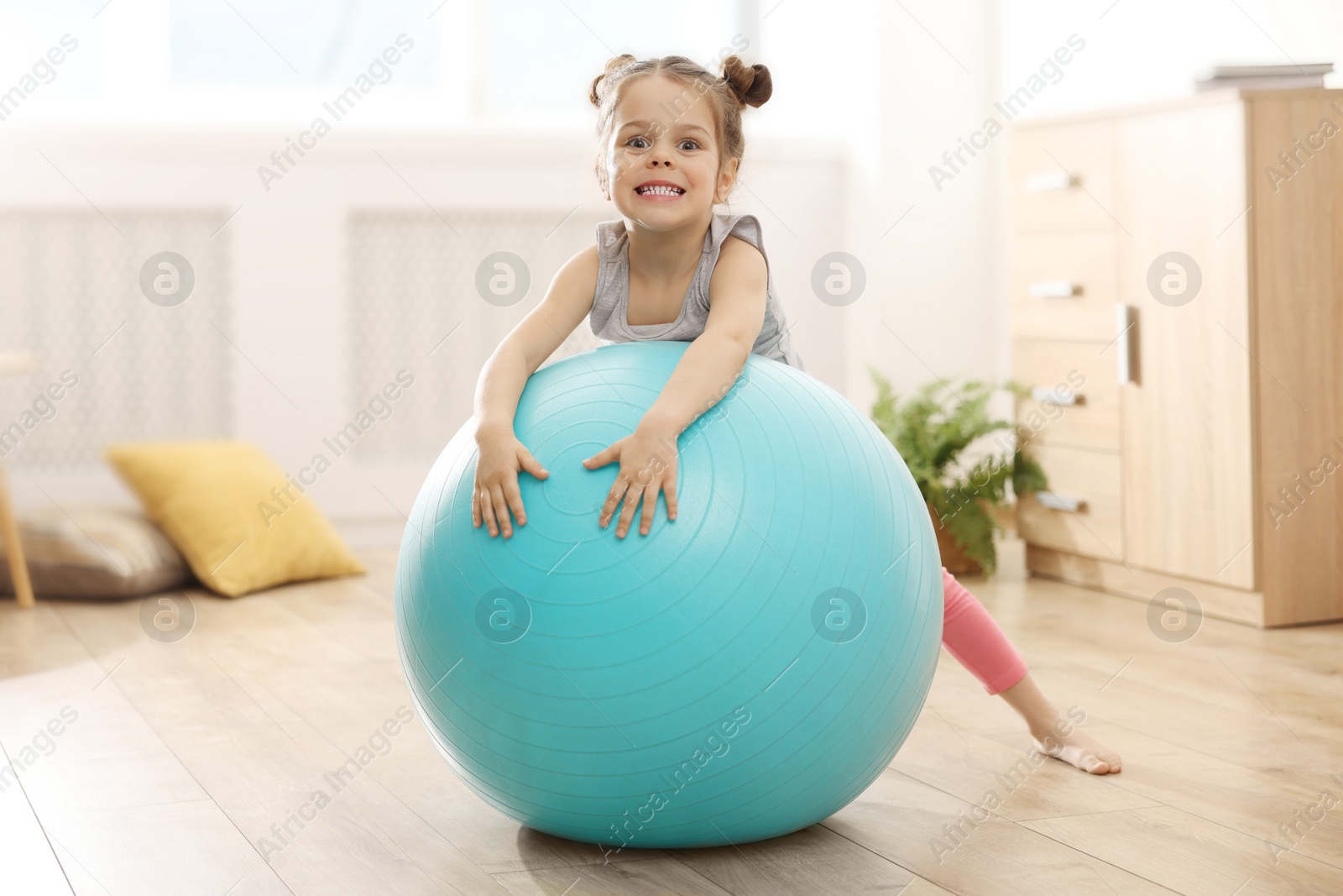 Photo of Little cute girl doing exercises with fitness ball at home