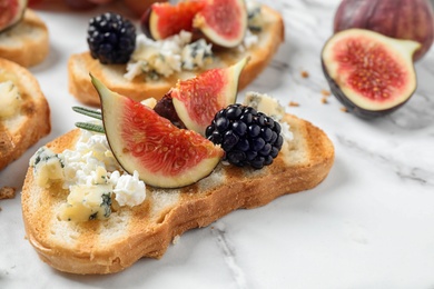 Photo of Bruschettas with cheese, figs and blackberries served on white table, closeup