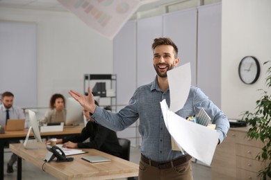 Happy dismissed man throwing up paper sheets at office