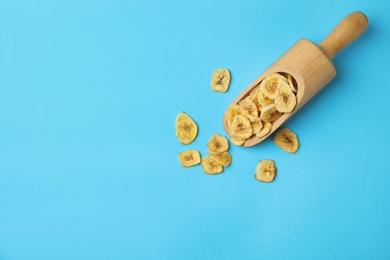 Photo of Wooden scoop with banana slices on color background, top view with space for text. Dried fruit as healthy snack