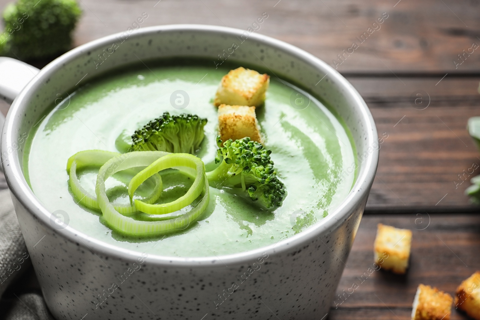 Photo of Fresh vegetable detox soup made of broccoli with croutons in dish on table, closeup