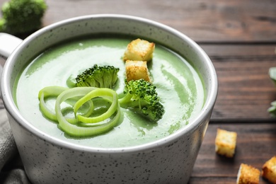 Photo of Fresh vegetable detox soup made of broccoli with croutons in dish on table, closeup