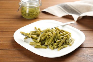 Photo of Delicious canned green beans on wooden table