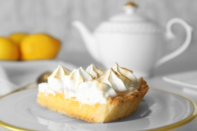 Plate with piece of delicious lemon meringue pie on white table