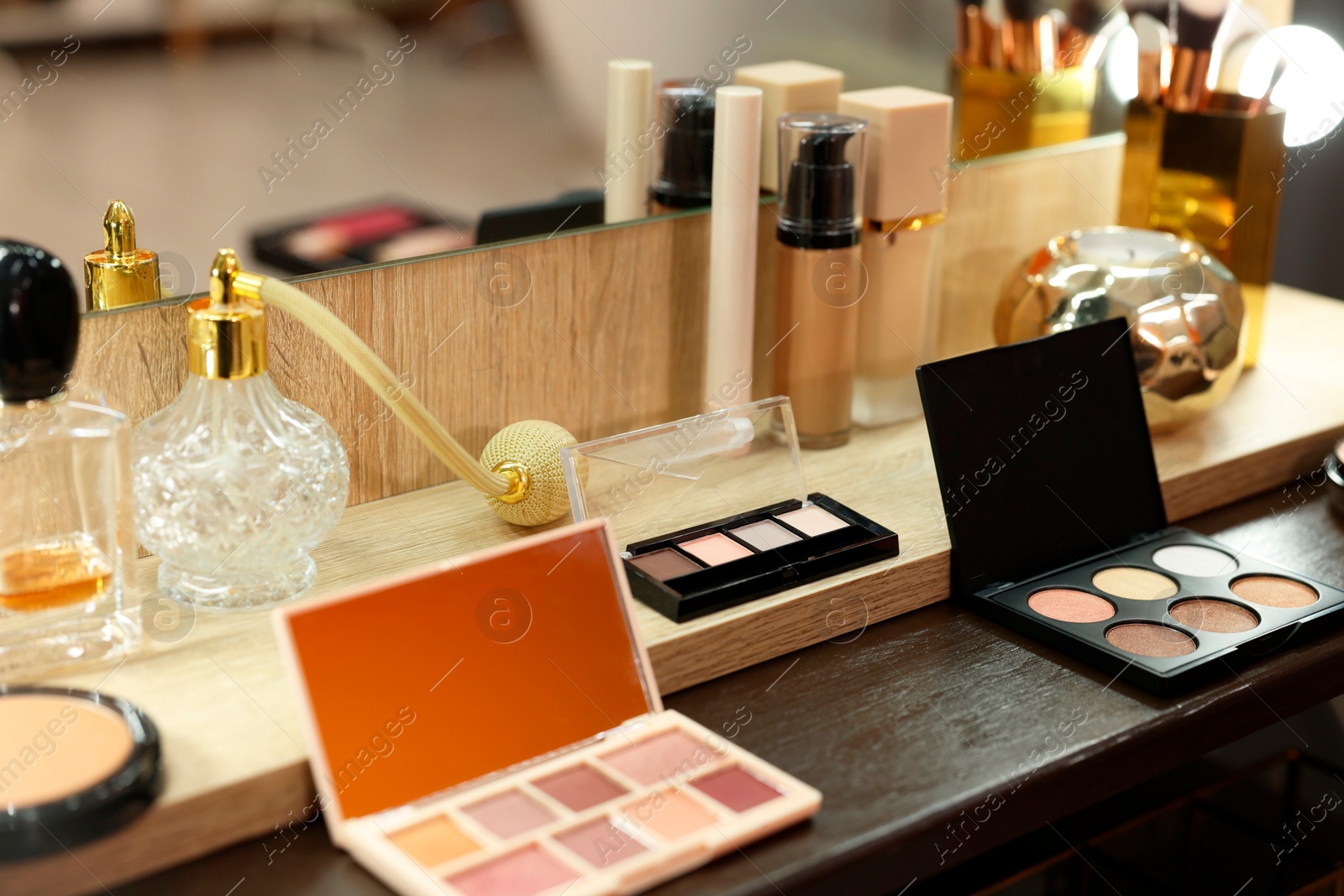 Photo of Makeup room. Cosmetic products and perfumes on wooden dressing table indoors